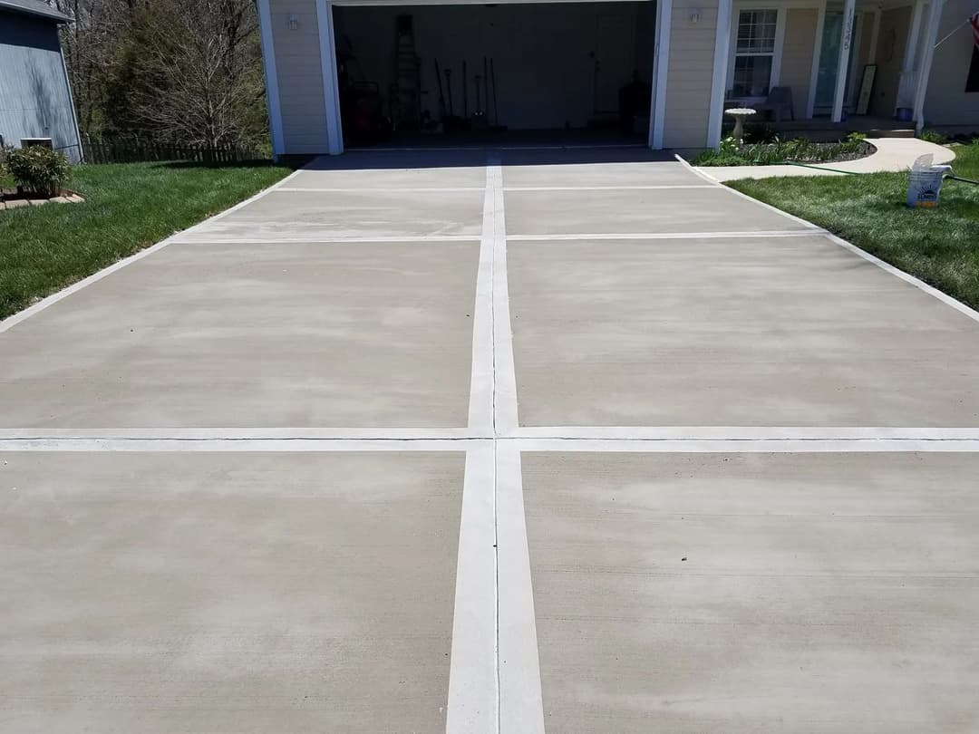 Freshly poured concrete driveway with distinct lines and a neatly maintained front yard.