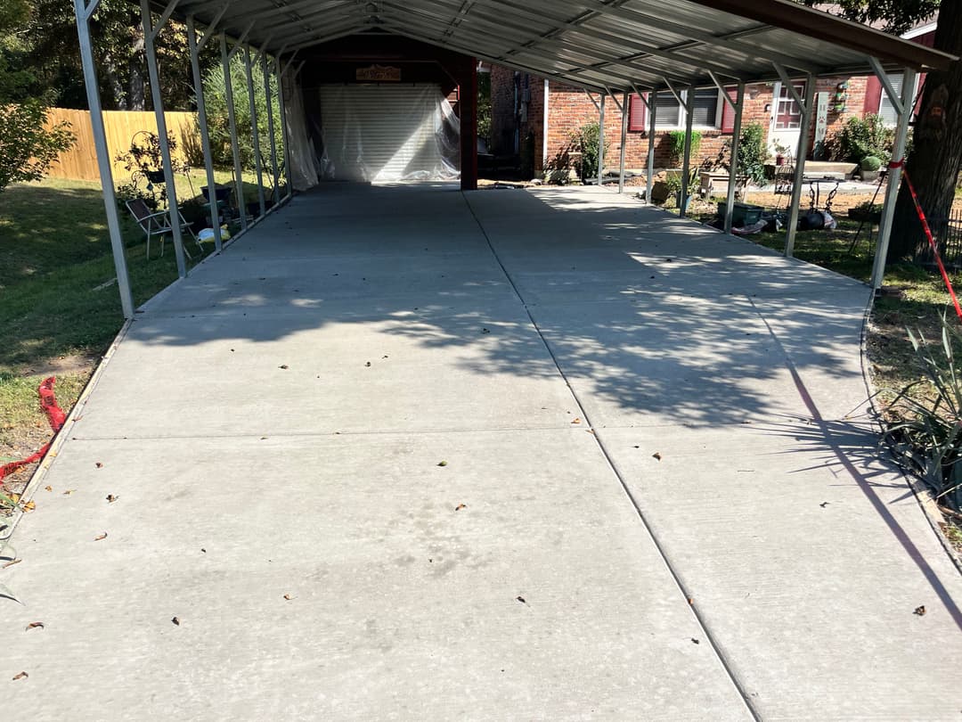 Paved carport with clean concrete surface and shaded area in residential yard.