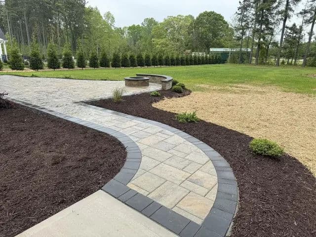 Landscaped garden with stone pathway, patio seating, and mulched flower beds.